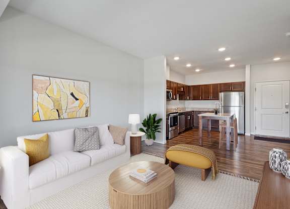 A modern living room with a white sofa and a yellow ottoman at EastGate Apartments, Minnesota