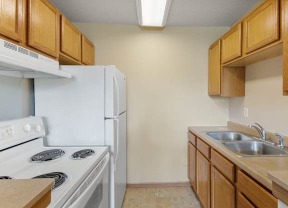 A kitchen with a white stove and a white refrigerator.