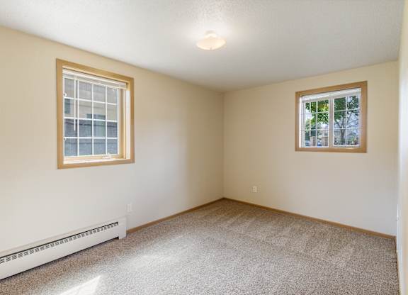A room with a window and a carpeted floor.