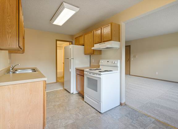 A kitchen with white appliances and wooden cabinets.