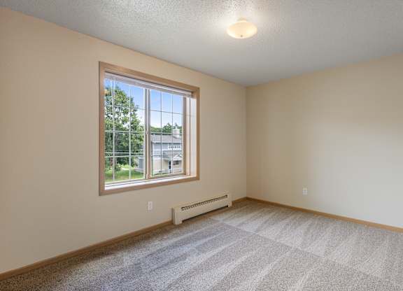 A room with a window and a carpeted floor.