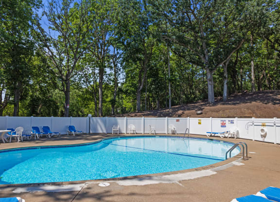 a swimming pool with chairs around it and trees in the background at Heritage Hills Apartments, Minnesota, 55437