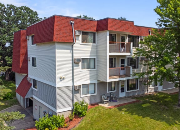 a white and red apartment building with a yard and trees at Heritage Hills Apartments, Minnesota, 55437