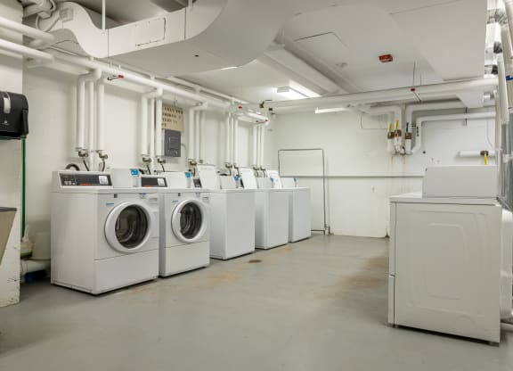 a row of washing machines and dryers in a laundry room
