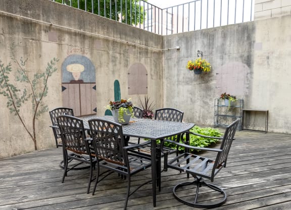 a patio with a table and chairs against a wall