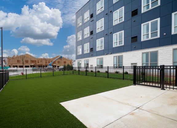 the yard of an apartment building with a green lawn and a fence at The Landing at Amber Fields Apartments, Rosemount