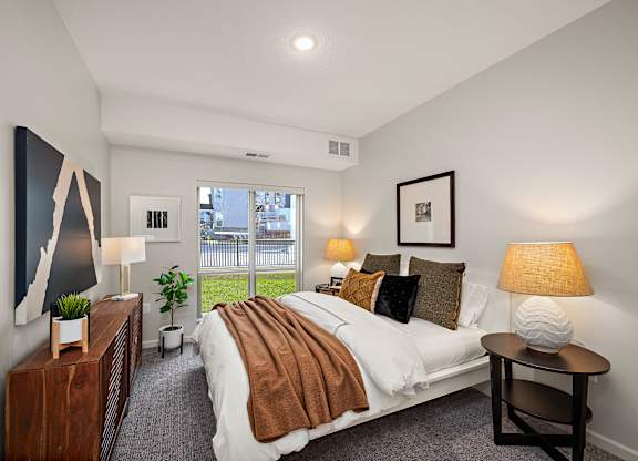 A bedroom with a large bed and a painting on the wall at The Landing at Amber Fields Apartments, Minnesota