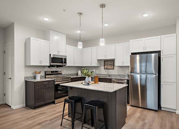 an open kitchen with a large island and stainless steel refrigerator at The Landing at Amber Fields Apartments, Rosemount, Minnesota