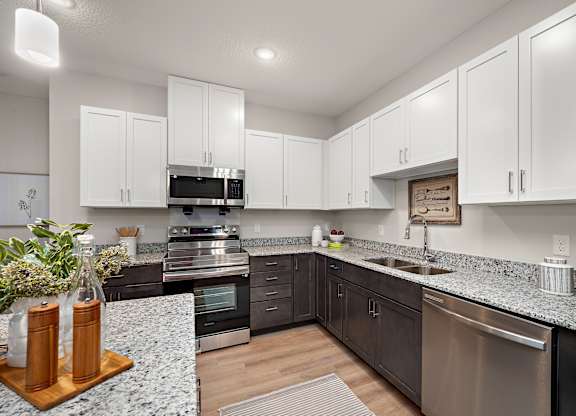 a kitchen with white cabinets and granite counter tops and stainless steel appliances at The Landing at Amber Fields Apartments, Rosemount, MN