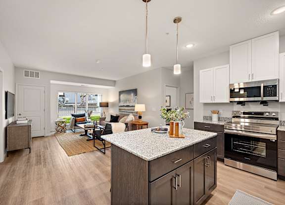 A modern kitchen with dark wood cabinets and a granite countertop at The Landing at Amber Fields Apartments, Rosemount, MN