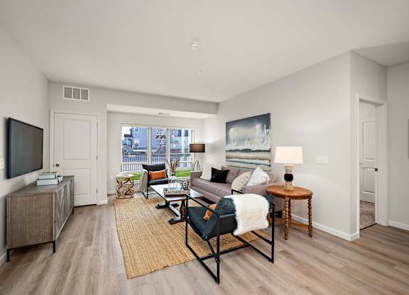 A living room with a couch, chair, and television at The Landing at Amber Fields Apartments, Rosemount, MN, 55068