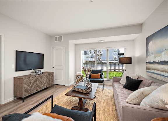 A living room with a brown sofa and a wooden coffee table at The Landing at Amber Fields Apartments, Minnesota, 55068
