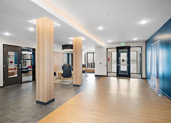 A hallway with a black chair and a wooden column at The Landing at Amber Fields Apartments, Rosemount, 55068