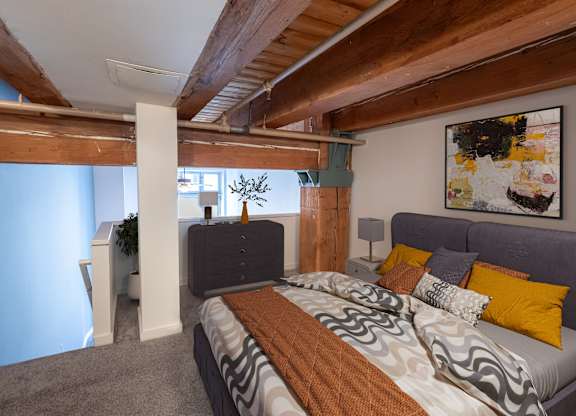 a bedroom with a bed and a couch in a room with exposed beams