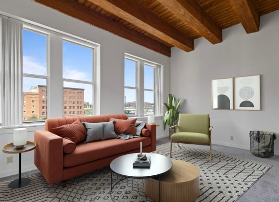 a living room with a couch and a coffee table and three windows