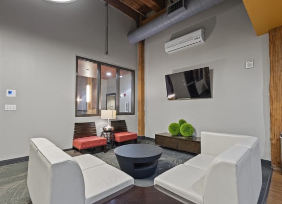 a living room with white furniture and a tv on the wall