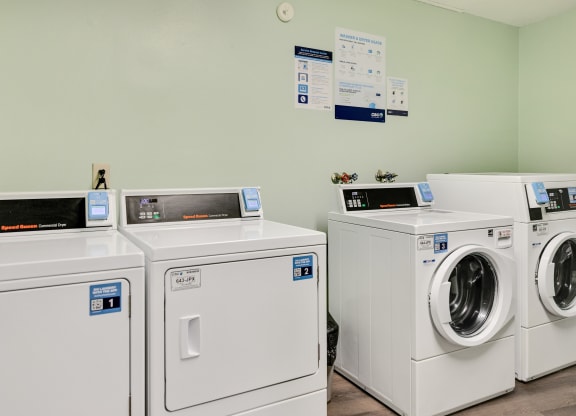 a row of washing machines and dryers in a laundry room