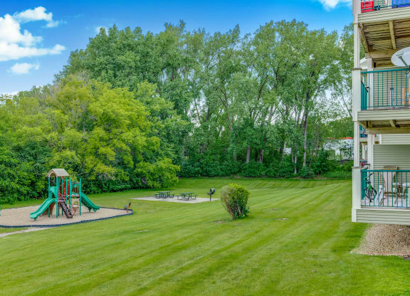 the backyard of a condo with a playground and a picnic area