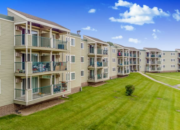 an exterior view of an apartment building with a green lawn