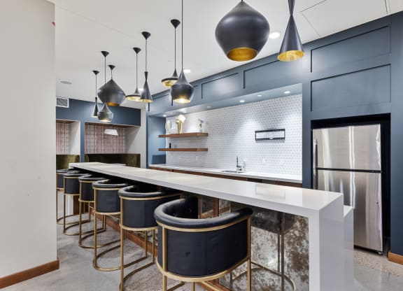 a large kitchen with a long counter top and a row of bar chairs