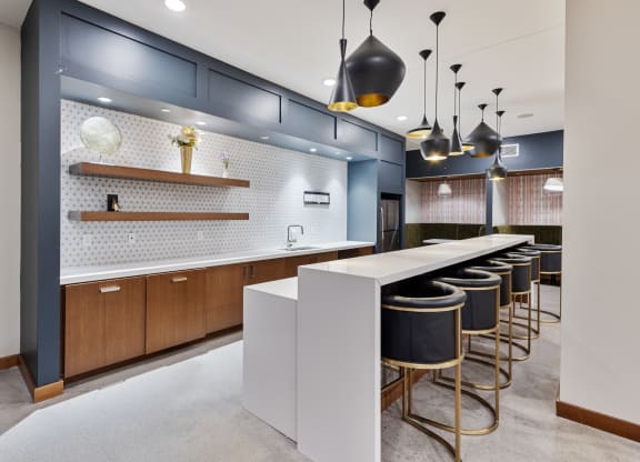 a communal kitchen with bar stools and blue and white tiles