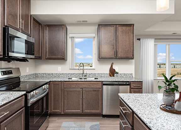A kitchen with brown cabinets and a black microwave at Decatur Landing Apartment, Brooklyn Park, MN, 55445