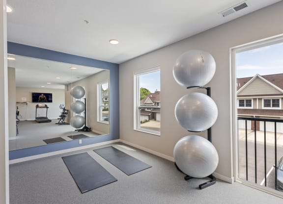 a fitness room with yoga mats and a large window at The Quill 55+ Apartments, Minnesota