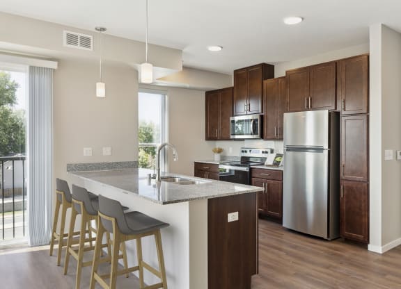 a kitchen with a large island and stainless steel refrigerator at The Quill 55+ Apartments, Hastings, MN