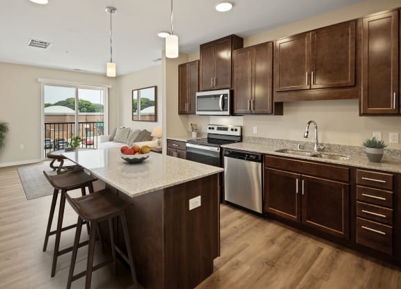 a kitchen with wooden cabinets and a marble counter top at The Quill 55+ Apartments, Hastings, MN, 55033