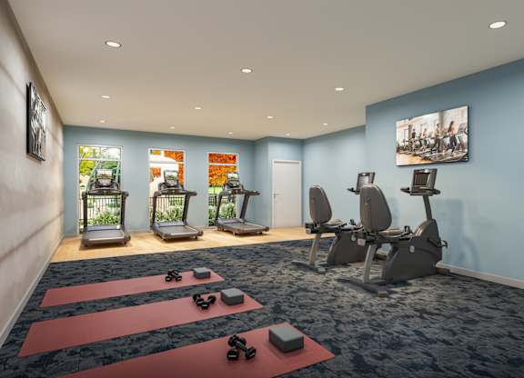 A gym with exercise equipment and yoga mats.
