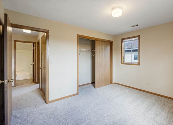 A room with a carpeted floor and a window with a picture frame hanging on the wall.