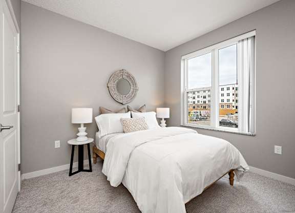 A bedroom with a large bed and a window overlooking a cityscape.