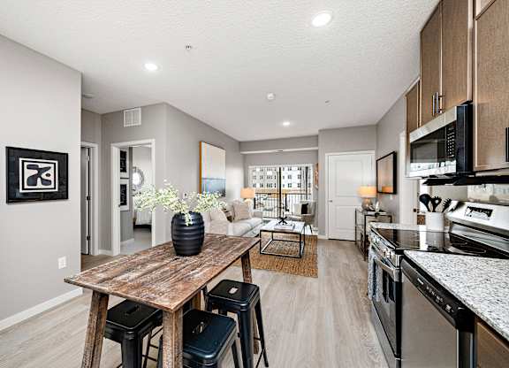 A modern kitchen with a wooden table and bar stools.