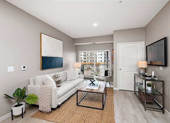 A living room with a white couch and a painting on the wall.