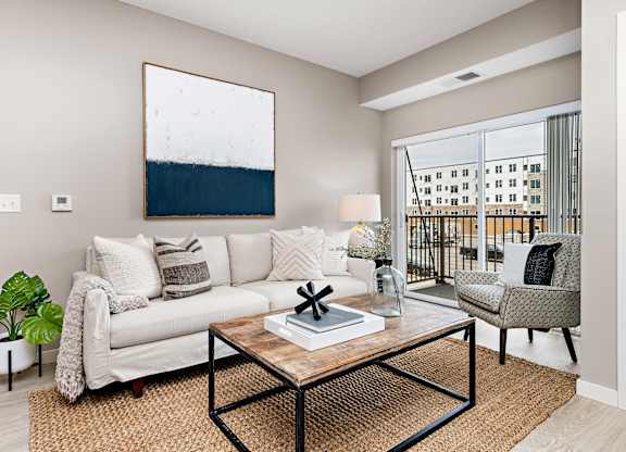 A living room with a white couch, a coffee table, and a large painting on the wall.