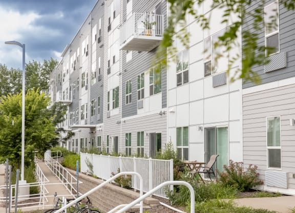 a large white apartment building with stairs and a fence at Technology Park Apartments, Minnesota, 55901