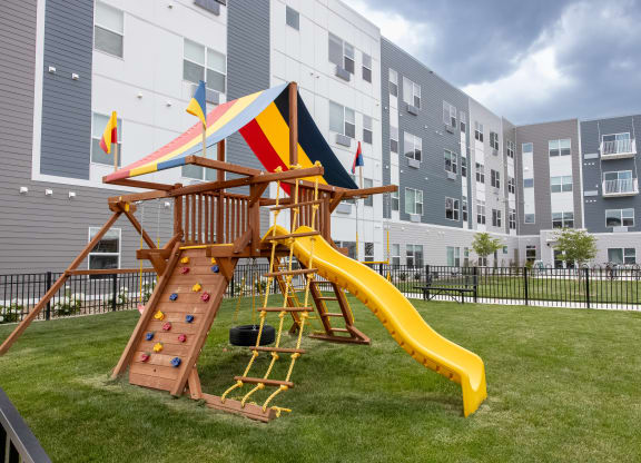 a playground with a swing set and a slide in an apartment building at Technology Park Apartments, Rochester