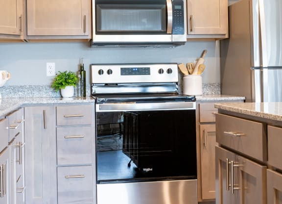 a modern kitchen with stainless steel appliances and white cabinets at Technology Park Apartments, Rochester, Minnesota