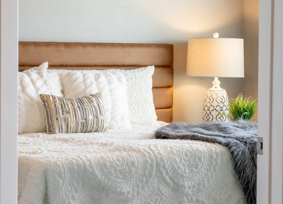 a bedroom with a bed and pillows and a lamp at Technology Park Apartments, Minnesota, 55901