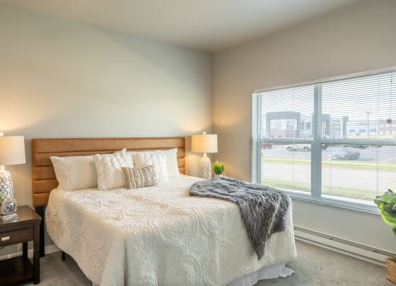 a bedroom with a bed and a large window at Technology Park Apartments, Rochester, MN, 55901