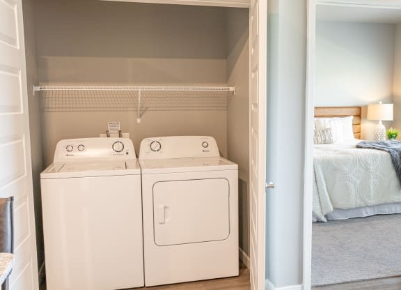 a room with a washer and dryer and a bedroom with a bed at Technology Park Apartments, Minnesota