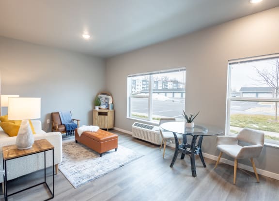a living room with a table and chairs and a large window at Technology Park Apartments, Rochester, MN