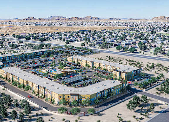 A large, modern building complex is surrounded by a parking lot and a residential neighborhood.