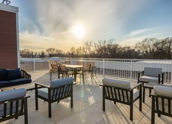 a patio with tables and chairs and a sunset in the background
