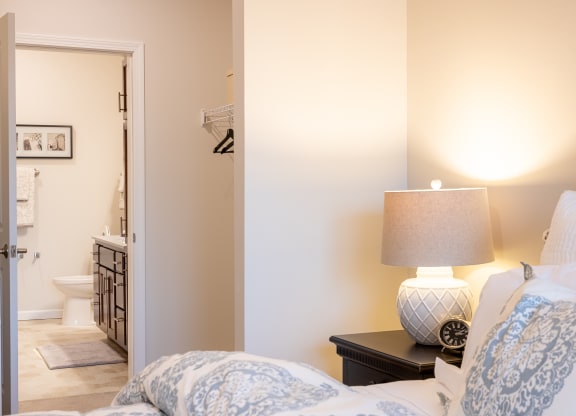 a bedroom with a bed and a lamp and a bathroom