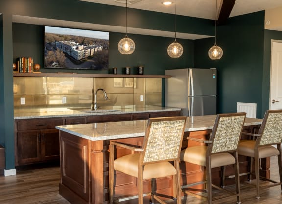 a kitchen with a bar and chairs and a refrigerator