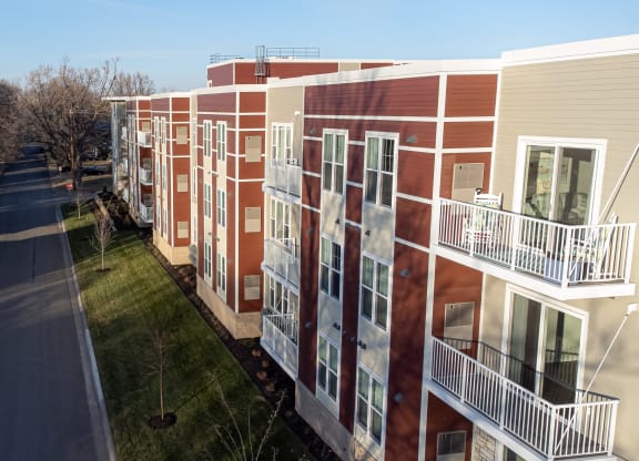 a row of red and white buildings with balconies and a road