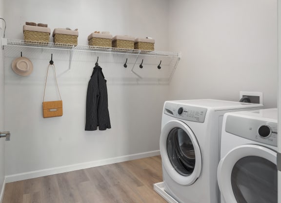 a washer and dryer in a laundry room with a white wall at The Landing at Amber Fields Apartments, Rosemount, 55068
