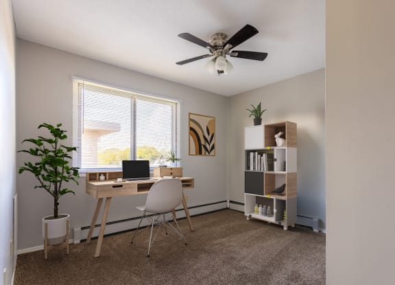 an office with a ceiling fan and a desk with a laptop