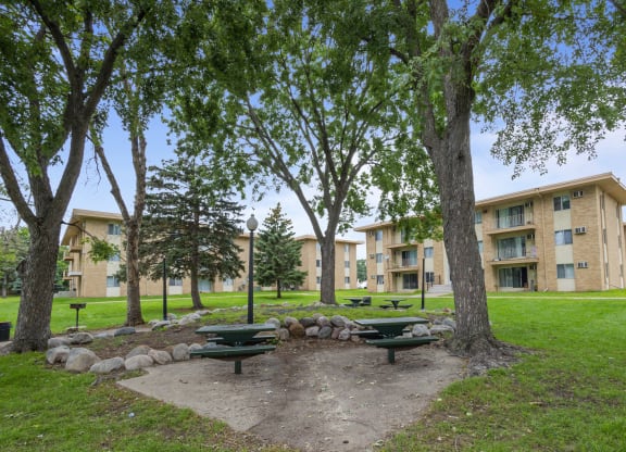 a park with picnic tables in front of an apartment building